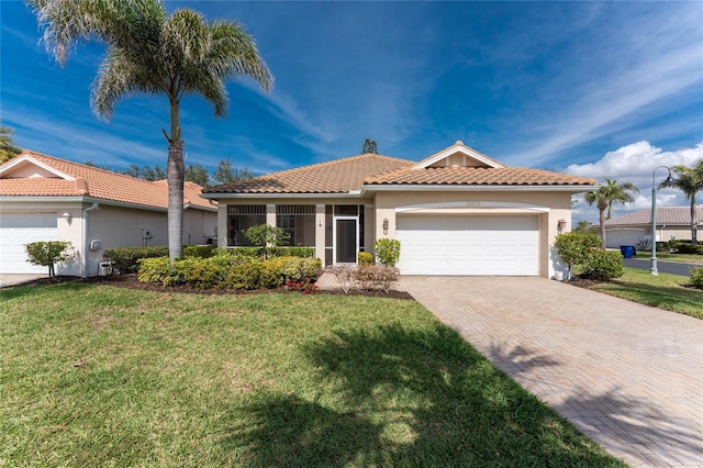 view of front of home featuring a front lawn, a tiled roof, stucco siding, decorative driveway, and a garage