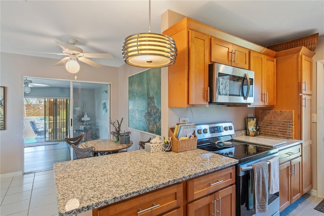 kitchen featuring light stone counters, hanging light fixtures, ceiling fan, and appliances with stainless steel finishes