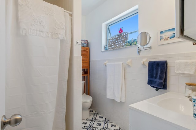 bathroom featuring tile patterned flooring, vanity, tile walls, and toilet