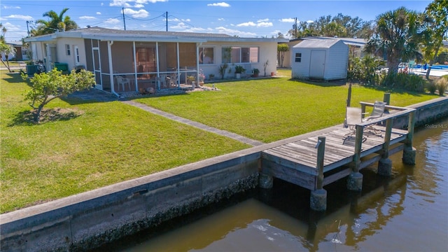 back of property with a water view, a yard, cooling unit, a storage unit, and a sunroom