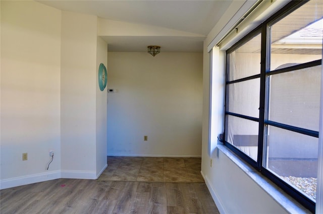 empty room featuring lofted ceiling, wood finished floors, and baseboards