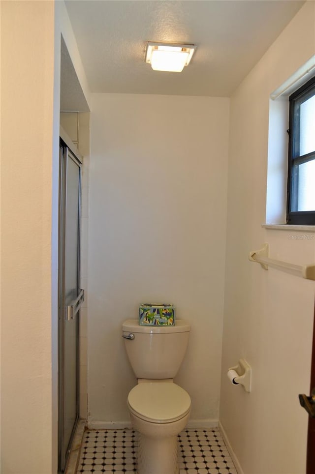 full bathroom with toilet, an enclosed shower, and baseboards