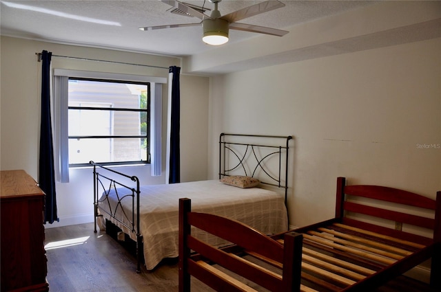 bedroom with dark wood finished floors, a textured ceiling, and baseboards