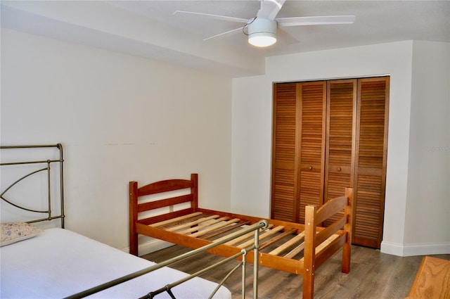 bedroom with dark wood-style flooring, a closet, a ceiling fan, and baseboards