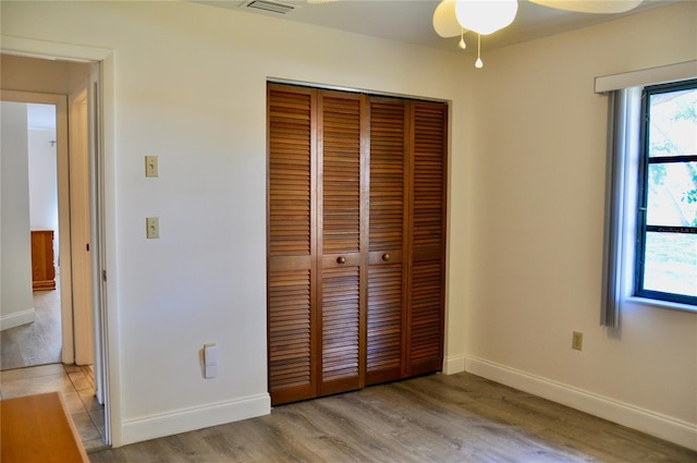 unfurnished bedroom with visible vents, a closet, light wood-style flooring, and baseboards