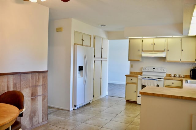 kitchen featuring light tile patterned floors, light countertops, cream cabinets, white appliances, and under cabinet range hood