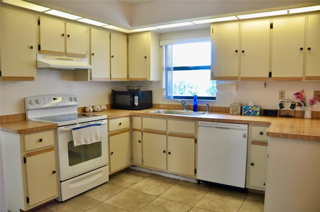 kitchen featuring light countertops, cream cabinets, a sink, white appliances, and under cabinet range hood