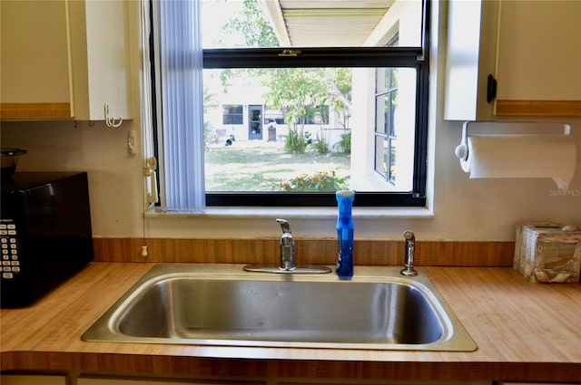 kitchen featuring black microwave, light countertops, and a sink