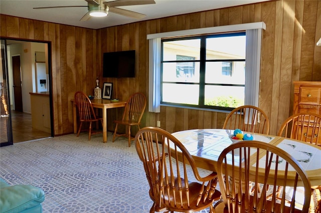 dining space with wood walls and ceiling fan