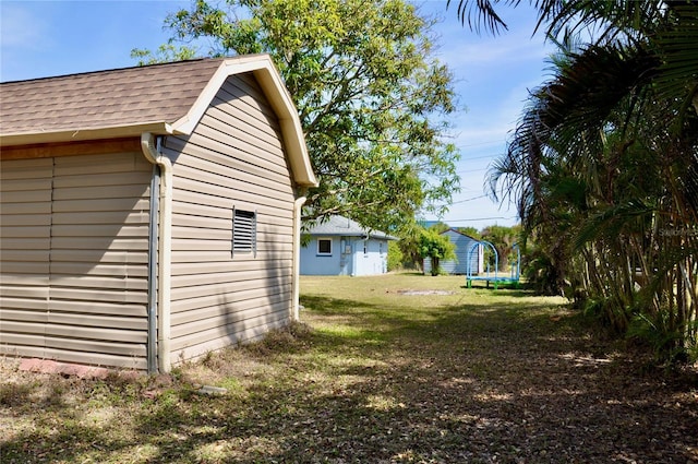 view of yard featuring a trampoline, an outbuilding, and a storage unit