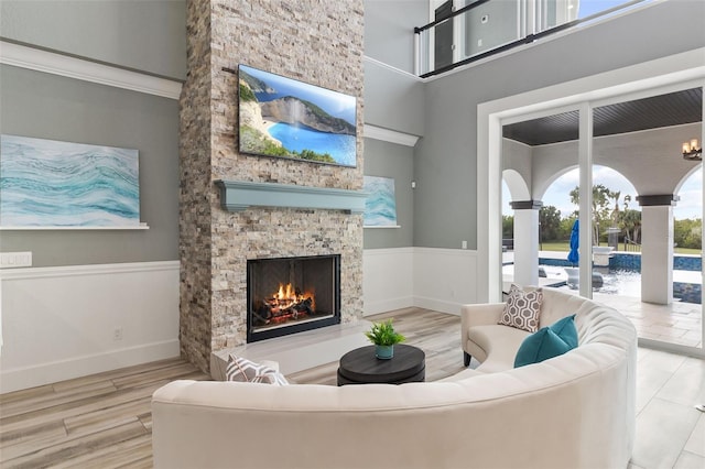 living room featuring wood-type flooring, a stone fireplace, and a towering ceiling