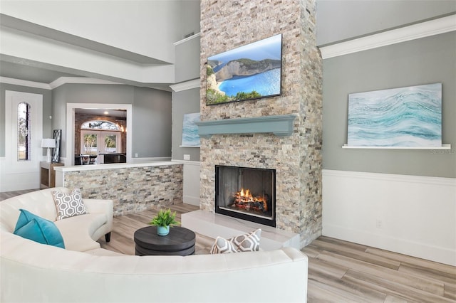 living room with hardwood / wood-style flooring, crown molding, and a fireplace