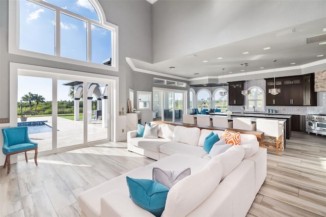 living room featuring light hardwood / wood-style floors, crown molding, and a towering ceiling