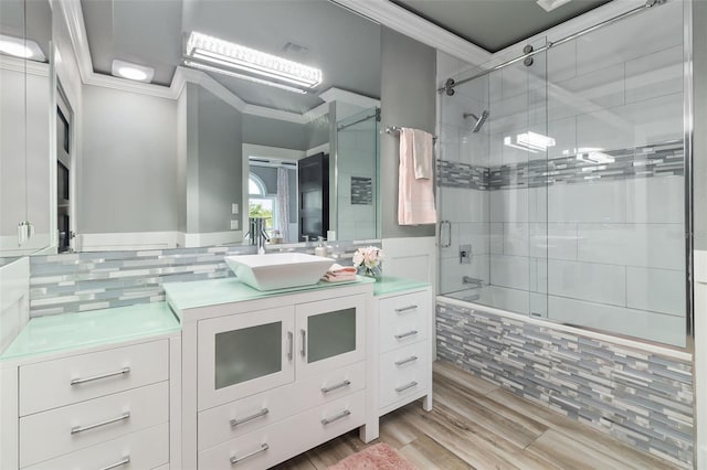 bathroom featuring hardwood / wood-style floors, backsplash, vanity, crown molding, and shower / bath combination with glass door