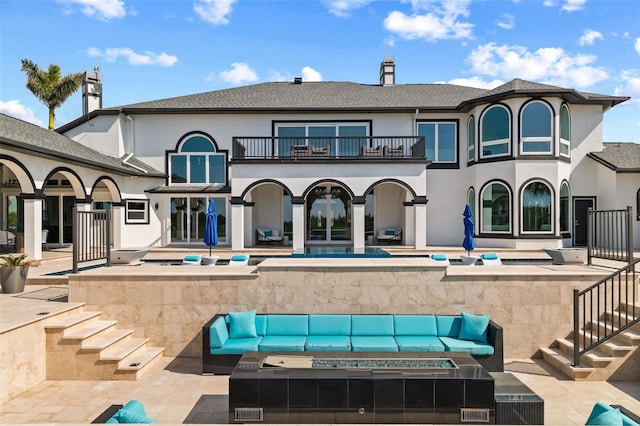 rear view of house featuring a balcony, a swimming pool with hot tub, a patio, and an outdoor hangout area