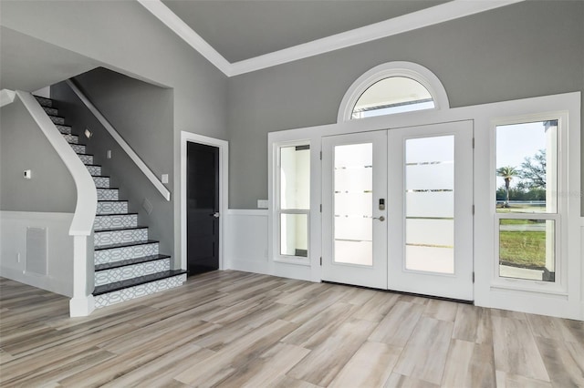 foyer with light wood-type flooring, french doors, and crown molding