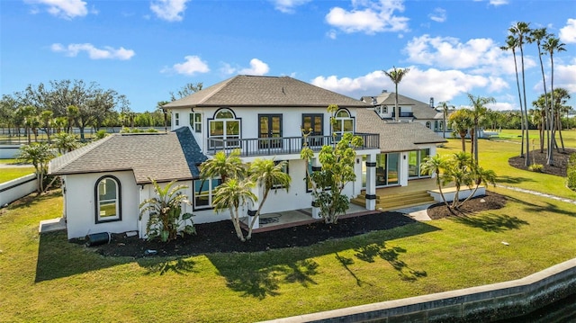 rear view of house featuring a balcony, a patio area, and a lawn