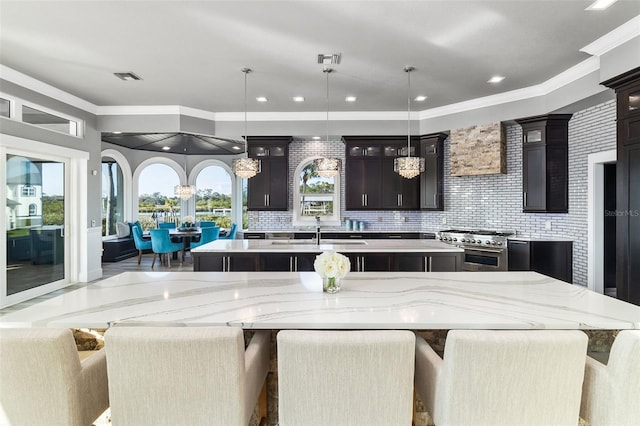 kitchen with a spacious island, decorative light fixtures, a breakfast bar area, and range with two ovens