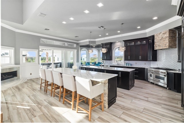 kitchen featuring hanging light fixtures, a spacious island, double oven range, light stone counters, and a kitchen breakfast bar