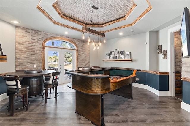 playroom featuring a tray ceiling, brick wall, dark hardwood / wood-style floors, and french doors