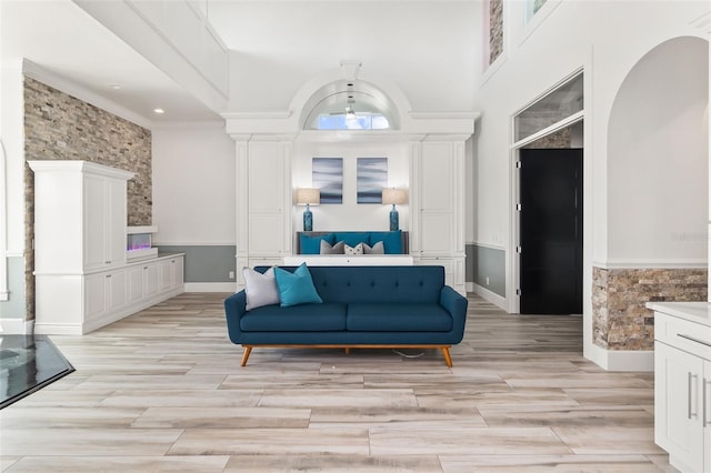 living area featuring light wood-type flooring, a high ceiling, and ornate columns