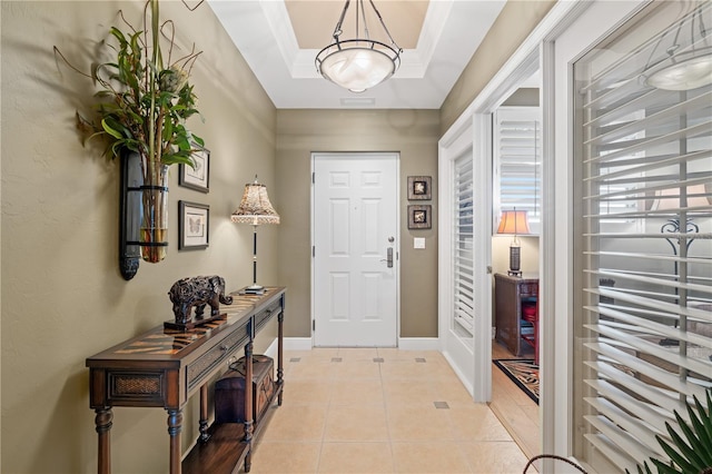 foyer entrance with light tile patterned floors, baseboards, and a tray ceiling