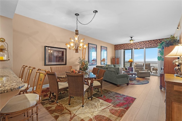 dining space with light wood-style flooring, baseboards, and a notable chandelier