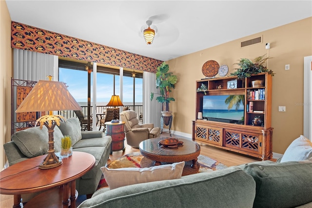 living area featuring baseboards, visible vents, and wood finished floors