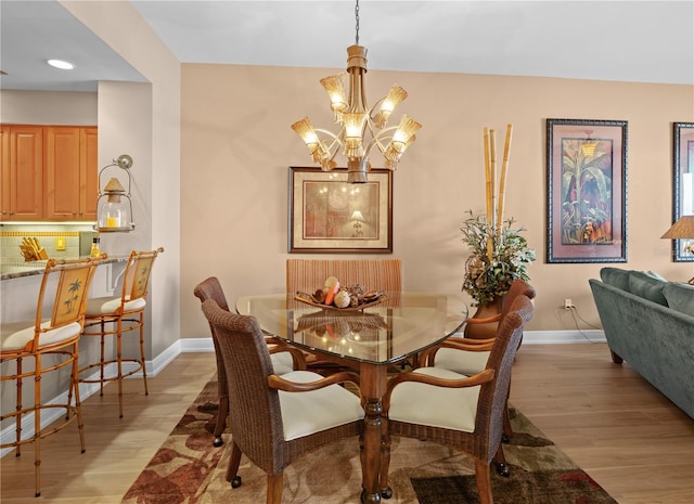 dining room with light wood finished floors, baseboards, and a notable chandelier