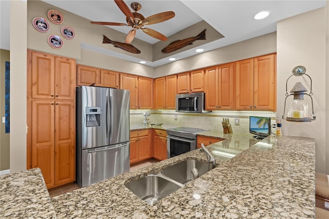 kitchen with appliances with stainless steel finishes, backsplash, a peninsula, and light stone counters