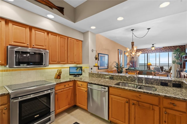 kitchen with appliances with stainless steel finishes, a sink, and light stone countertops