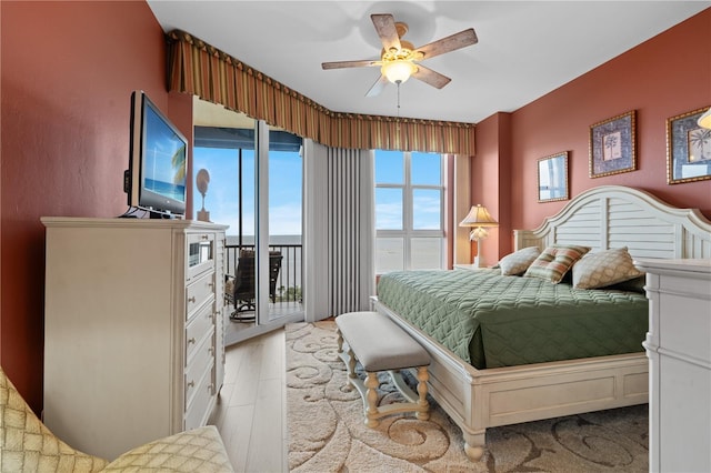 bedroom featuring access to exterior, light wood-style flooring, and a ceiling fan