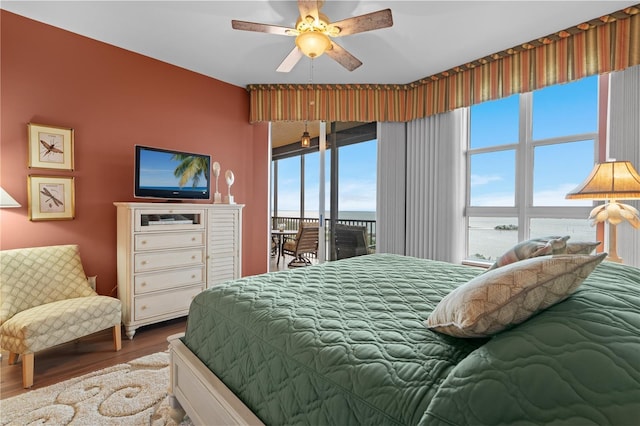 bedroom with access to exterior, ceiling fan, and wood finished floors