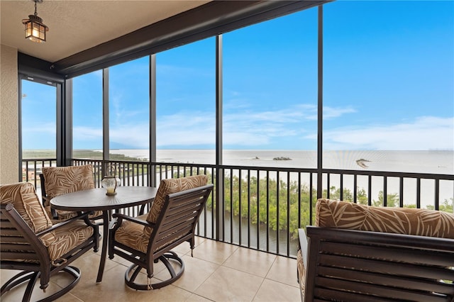 sunroom with a water view and a beach view