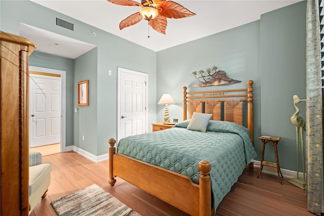 bedroom featuring ceiling fan, wood finished floors, visible vents, and baseboards