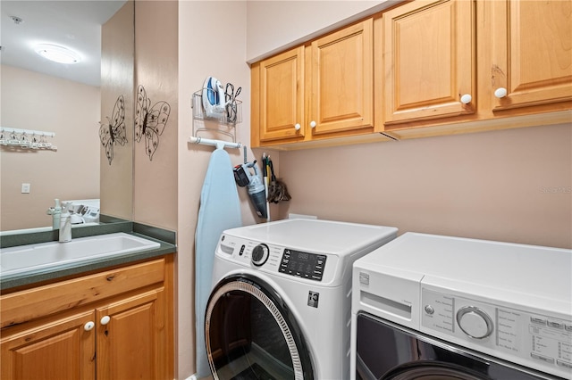 clothes washing area featuring a sink, washing machine and clothes dryer, and cabinet space