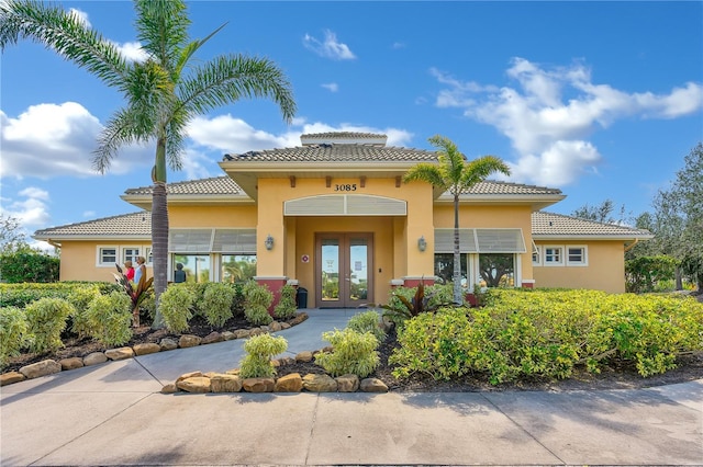 exterior space featuring stucco siding, a tiled roof, and french doors