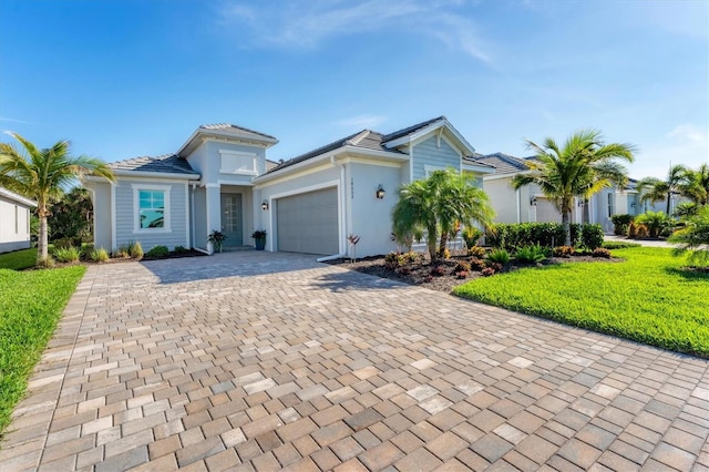 view of front of property with decorative driveway, an attached garage, stucco siding, and a front yard