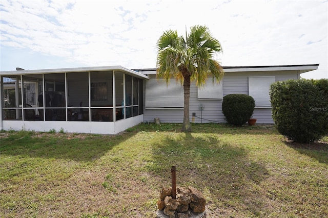 rear view of property featuring a sunroom and a yard