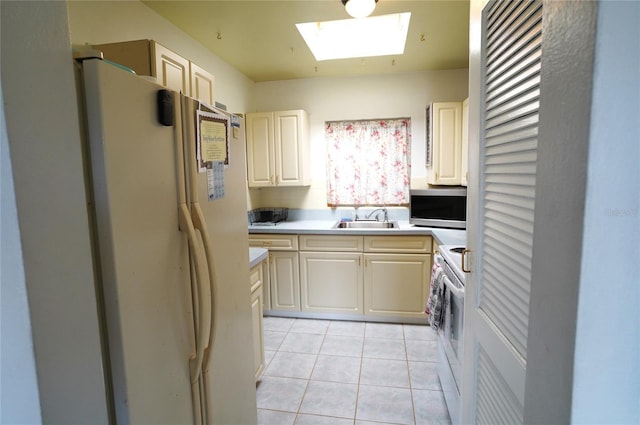 kitchen with light tile patterned flooring, white appliances, a skylight, and sink