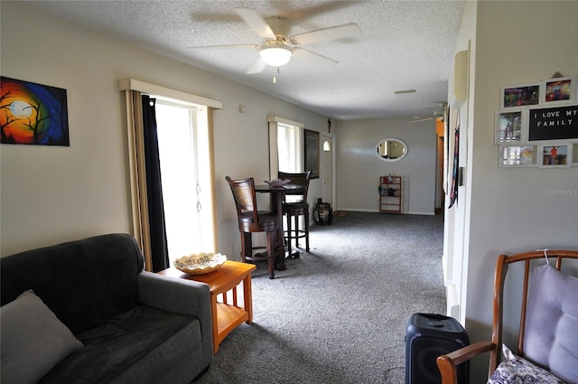 living room featuring ceiling fan, carpet floors, and a textured ceiling