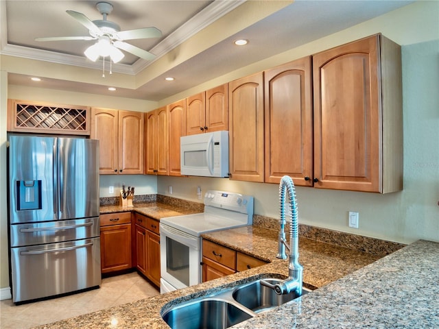 kitchen with sink, white appliances, crown molding, a tray ceiling, and stone countertops