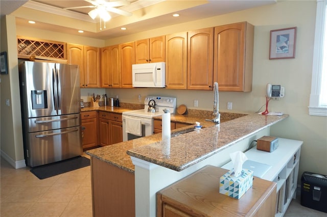 kitchen featuring kitchen peninsula, a tray ceiling, crown molding, light stone countertops, and white appliances