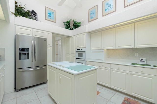 kitchen featuring double oven, a center island, stainless steel fridge with ice dispenser, and light tile patterned floors