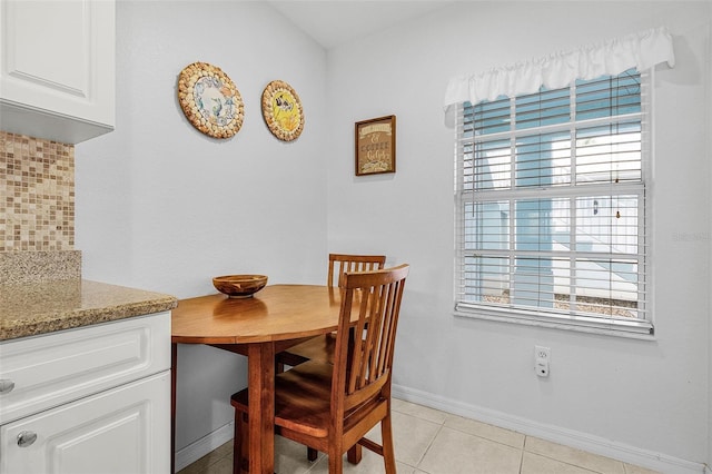 dining space with a wealth of natural light, light tile patterned floors, and baseboards