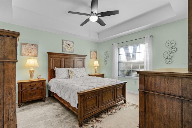 bedroom with ceiling fan, a tray ceiling, baseboards, and light tile patterned flooring