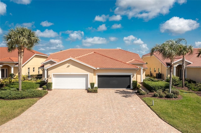 mediterranean / spanish-style home with a garage, central air condition unit, and a front lawn