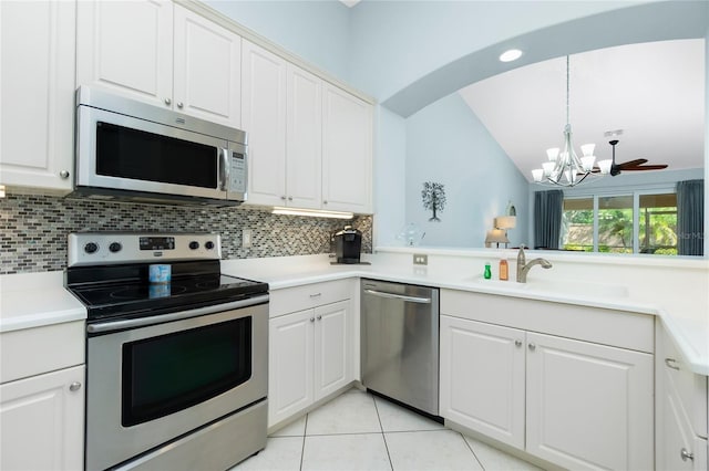 kitchen with white cabinets, hanging light fixtures, stainless steel appliances, and tasteful backsplash