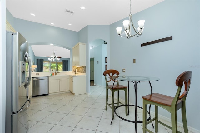 kitchen featuring hanging light fixtures, an inviting chandelier, backsplash, appliances with stainless steel finishes, and light tile patterned flooring