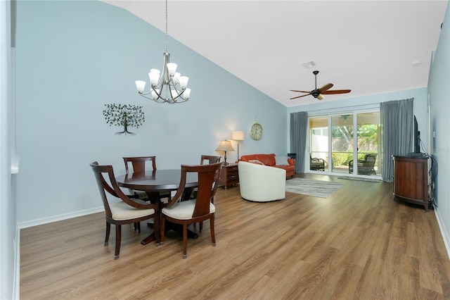 dining space with hardwood / wood-style flooring, ceiling fan with notable chandelier, and lofted ceiling